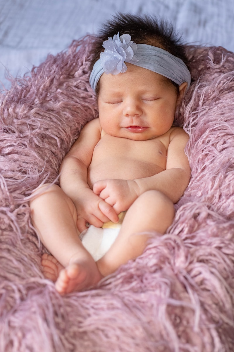 baby lying on pink textile